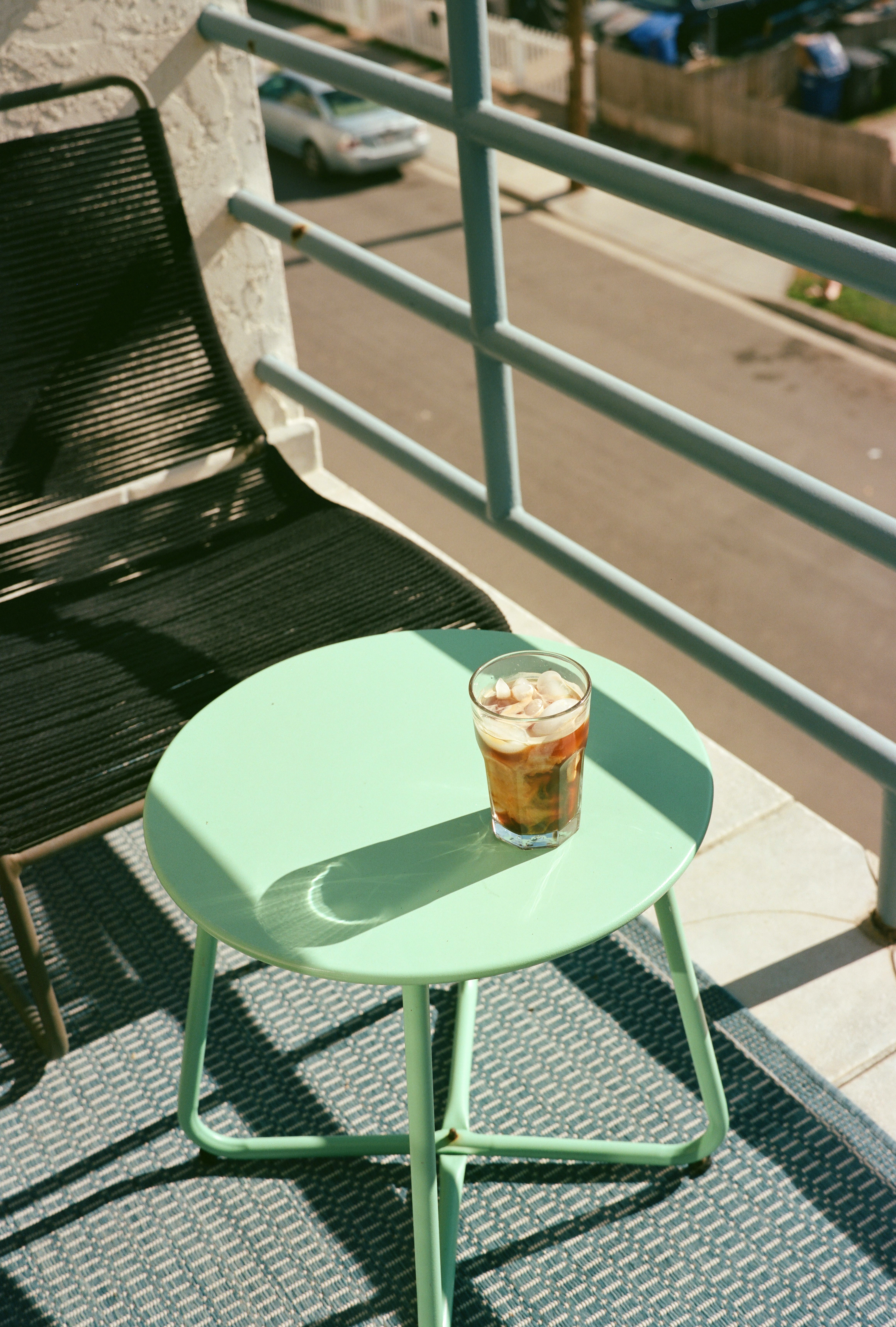 An iced americano with marbled milk sits in the sunlight.