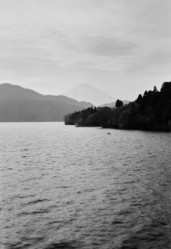 Mount Fuji is shown in the distance of a lake in Hakone.