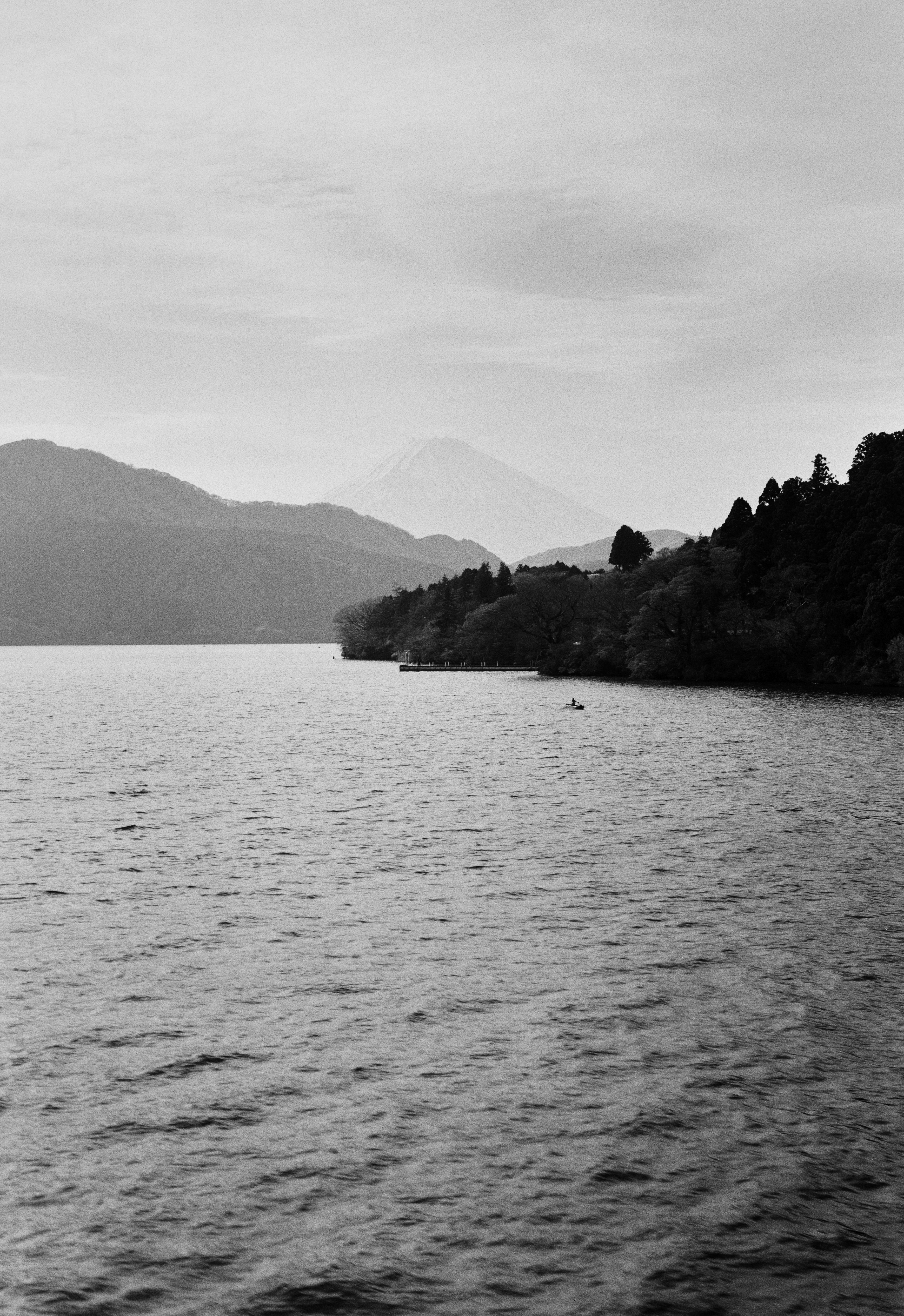 Mount Fuji is shown in the distance of a lake in Hakone.