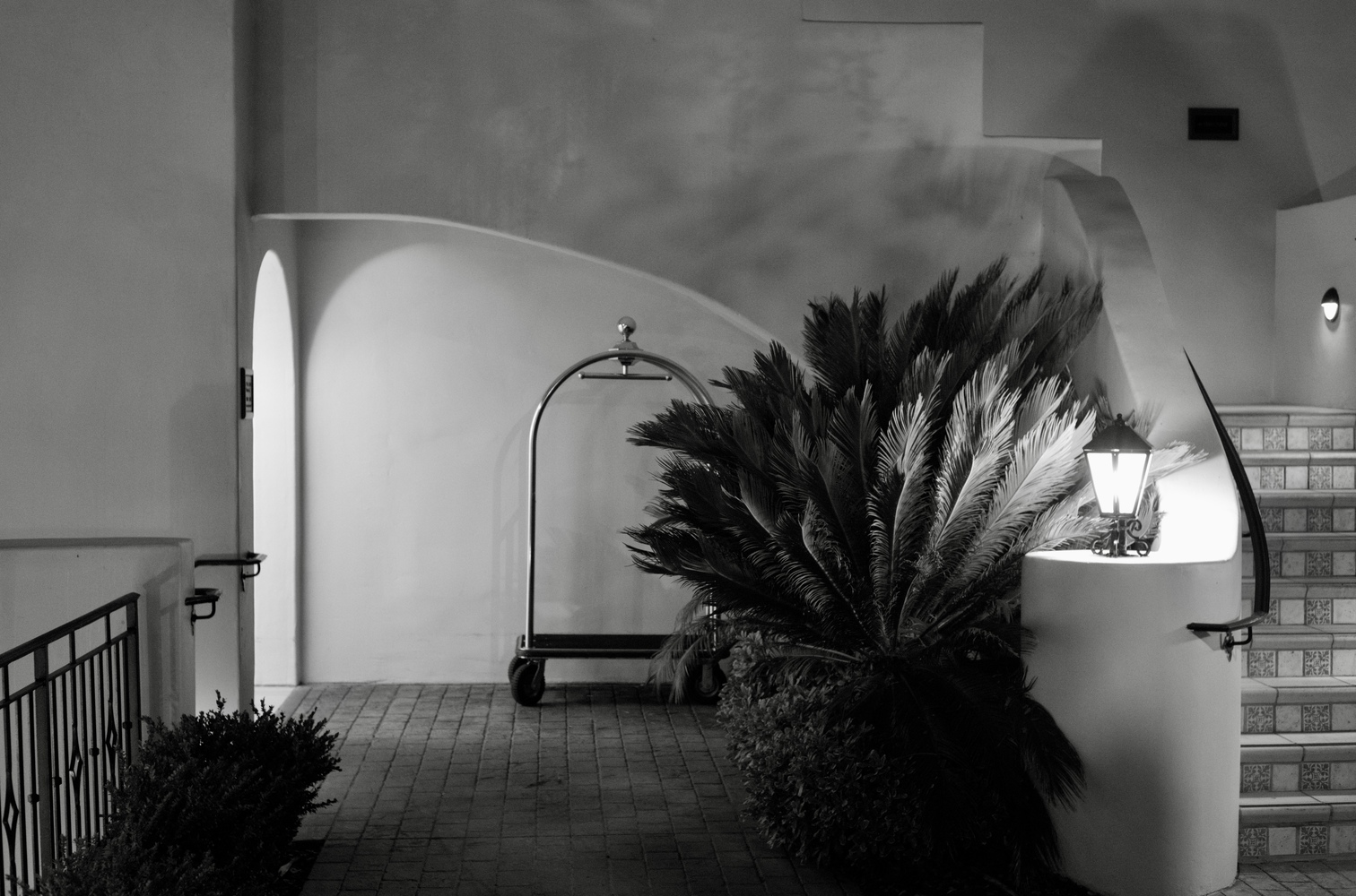 A black and white photo shows a bellhop's cart with no bellhop in sight.