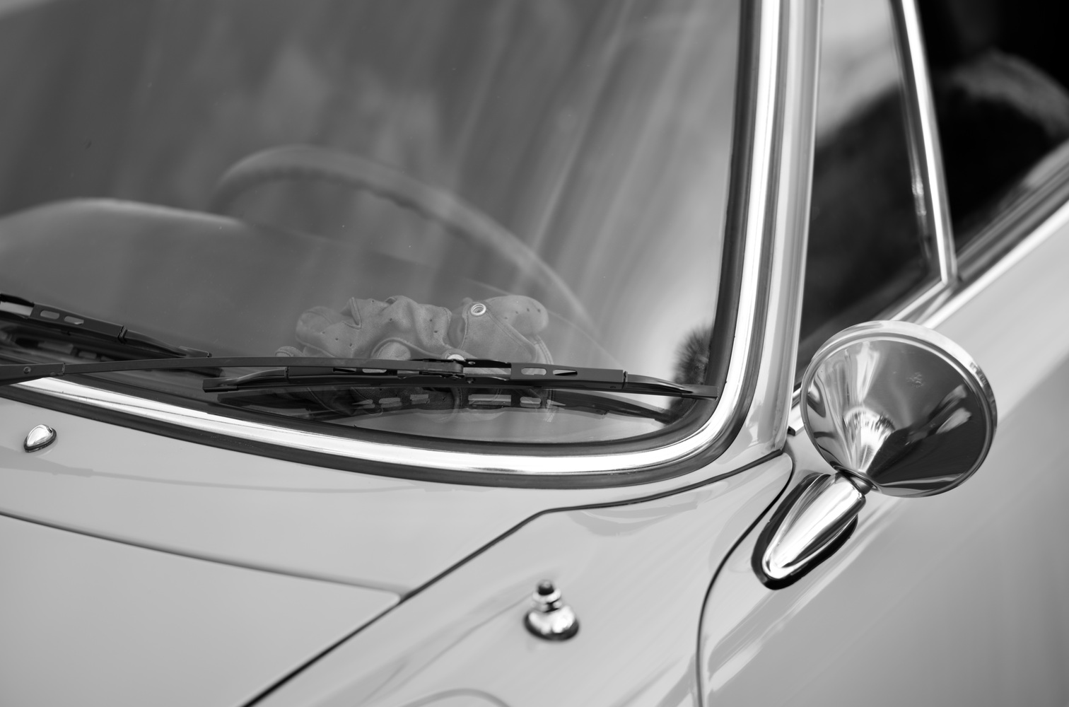 A pair of driving gloves rests on the dashboard of a vintage car.