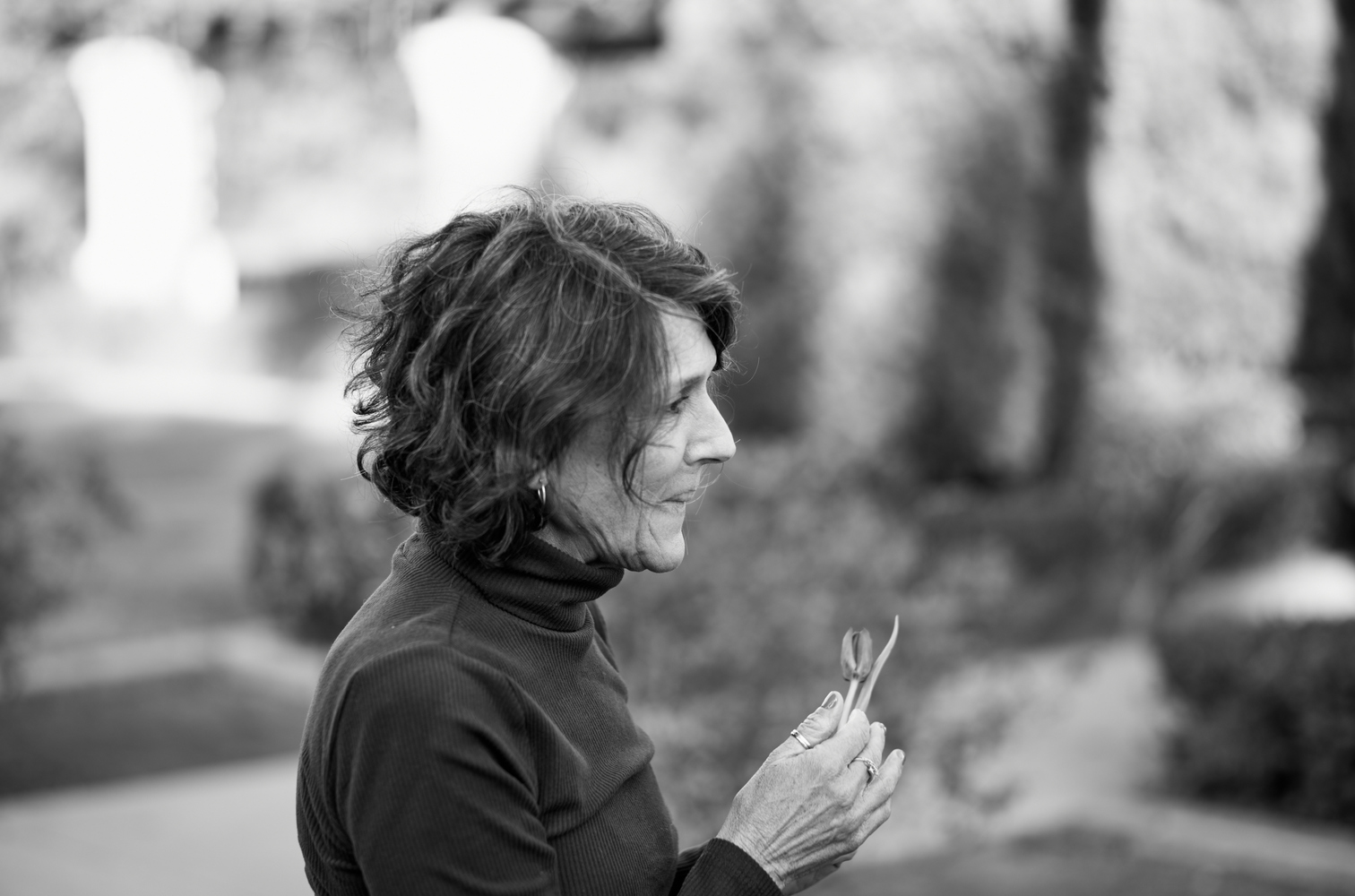 A woman contemplates as she holds a tulip