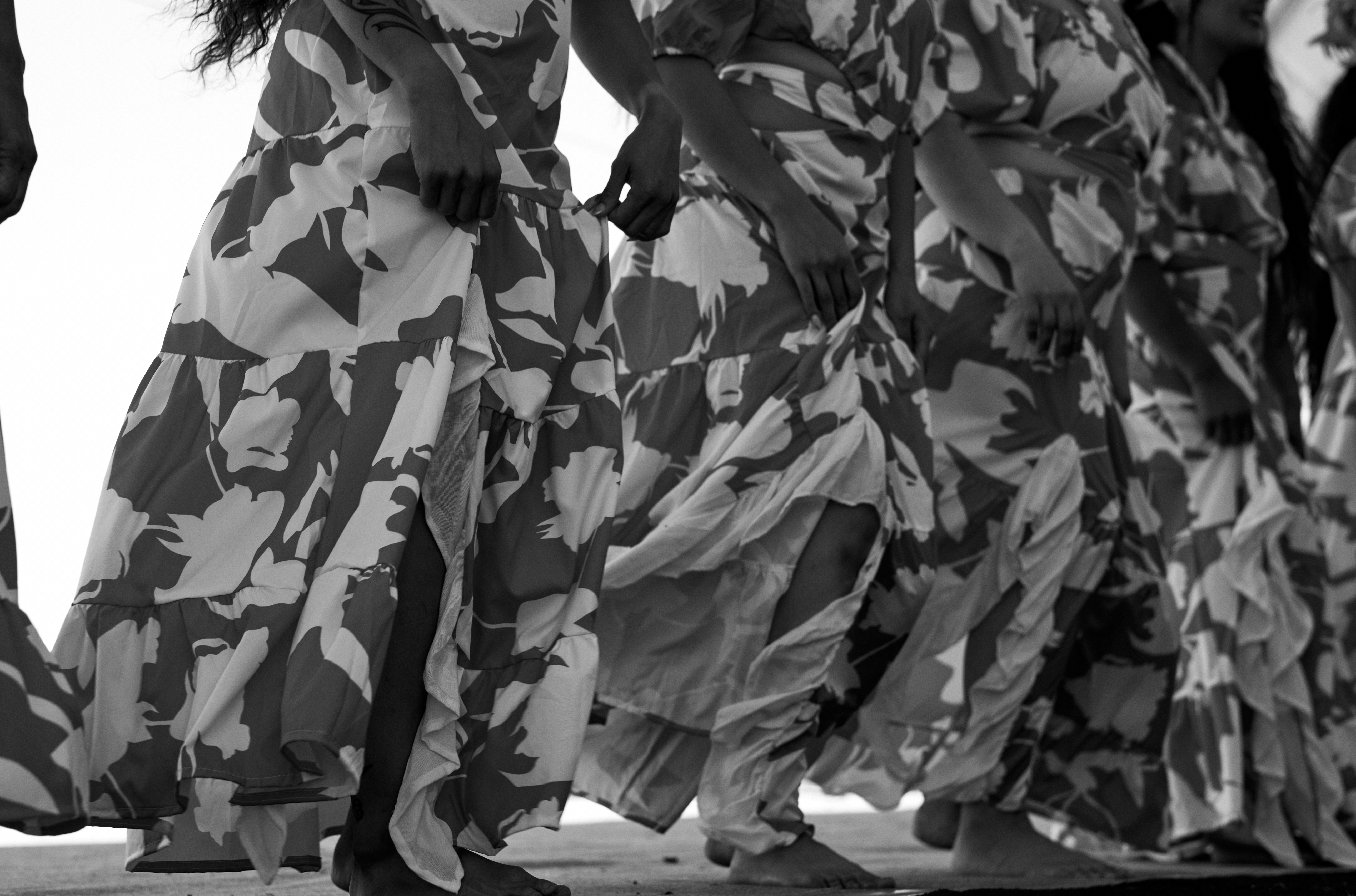 A line of dancers adorned in dresses moves in a hula.