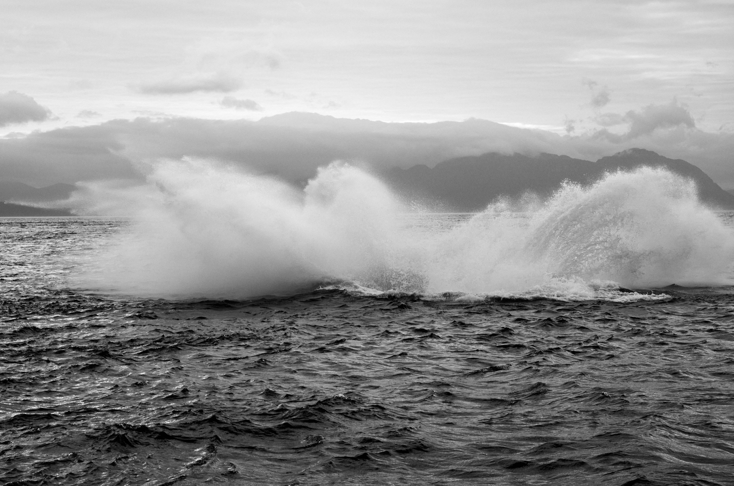 A black and white photograph shows a large splash in the ocean