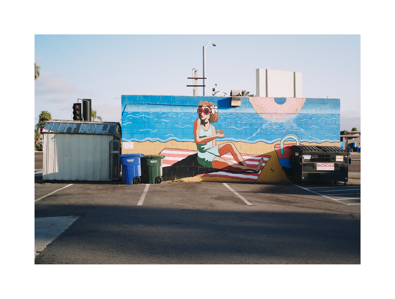 A mural shows a woman on the beach eating a donut.